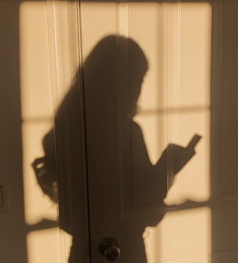 the shadow of a person standing in front of a door holding a cell phone and looking at it