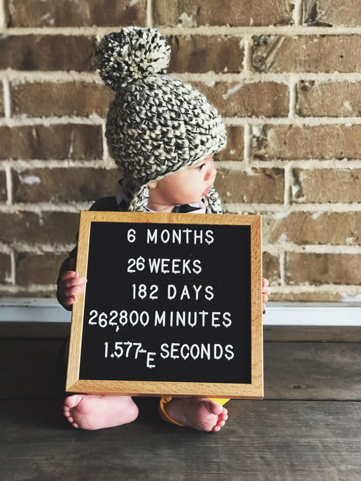 a small child holding a sign that says 8 months, 2 weeks and 3 minutes