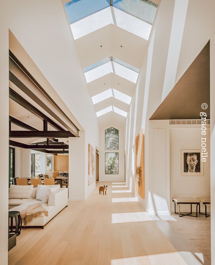 an open living room and dining area with skylights on the ceiling, hardwood flooring