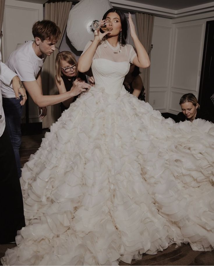 a woman in a wedding dress is surrounded by other people