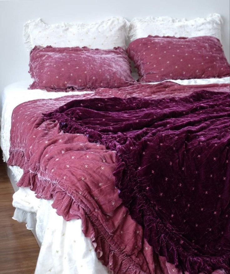 a bed with purple comforter and pillows on it