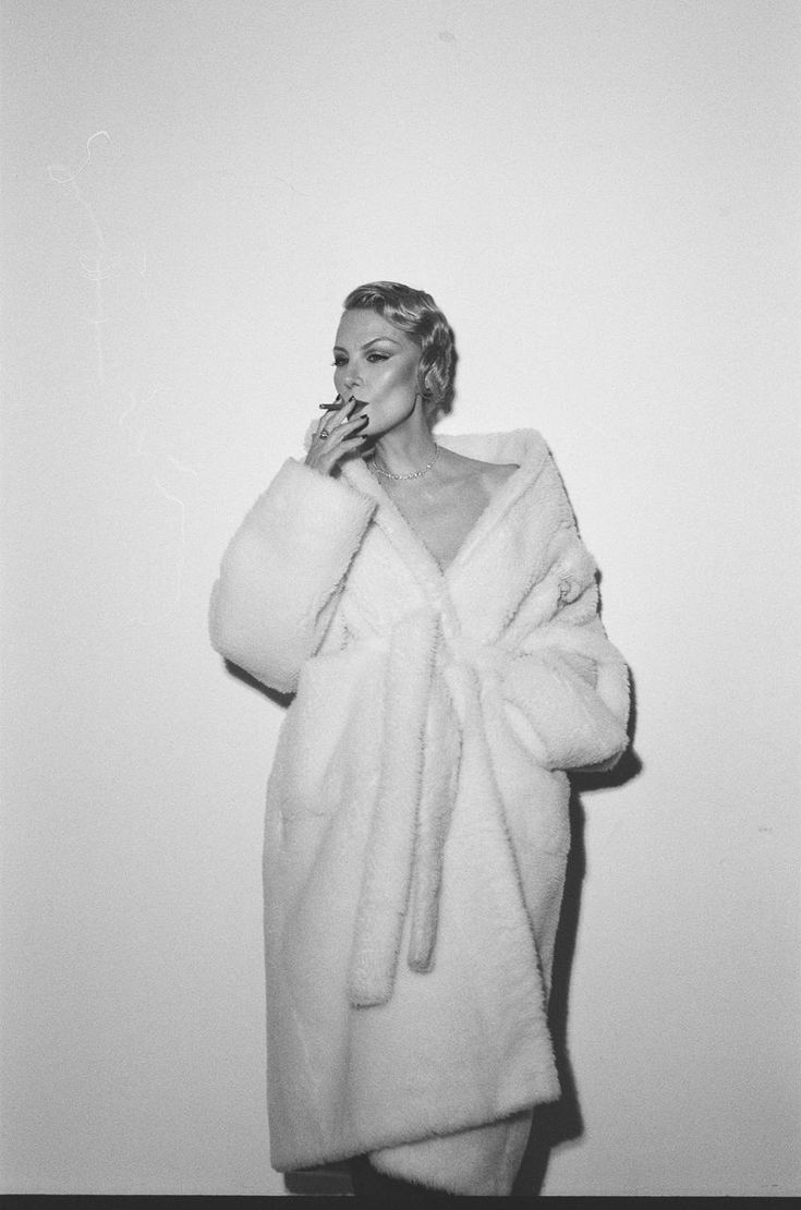 a black and white photo of a woman in a bathrobe brushing her teeth