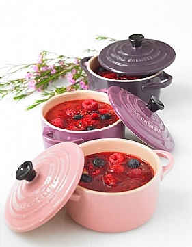 three pots filled with food sitting on top of a white table next to pink flowers