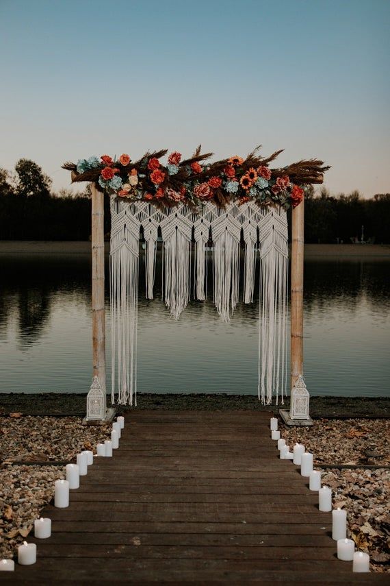 an outdoor ceremony setup with candles and flowers on the dock by the water at sunset