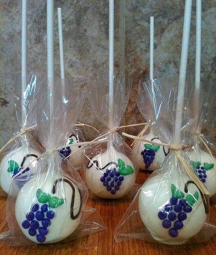 four white candles are wrapped in plastic and have grapes on them