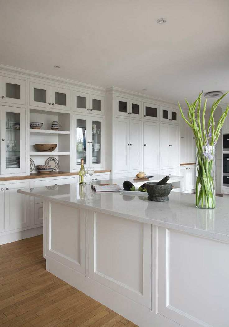 a large kitchen with white cabinets and counter tops, along with an island in the middle