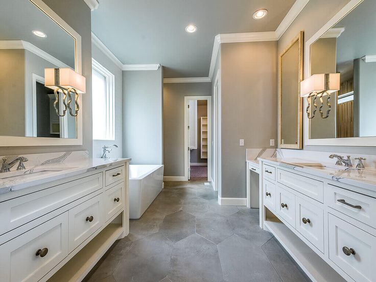 a large bathroom with two sinks, mirrors and bathtub in the middle of it