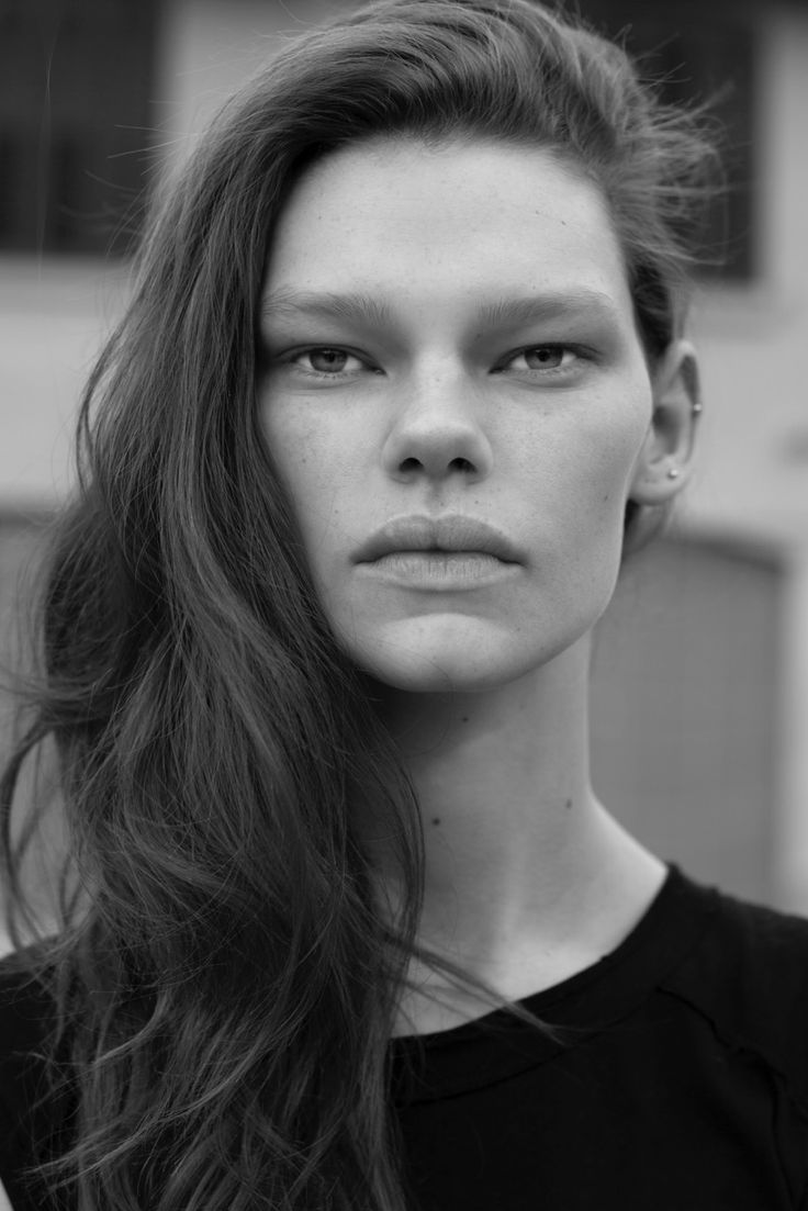 a black and white photo of a woman with long brown hair, wearing a black top