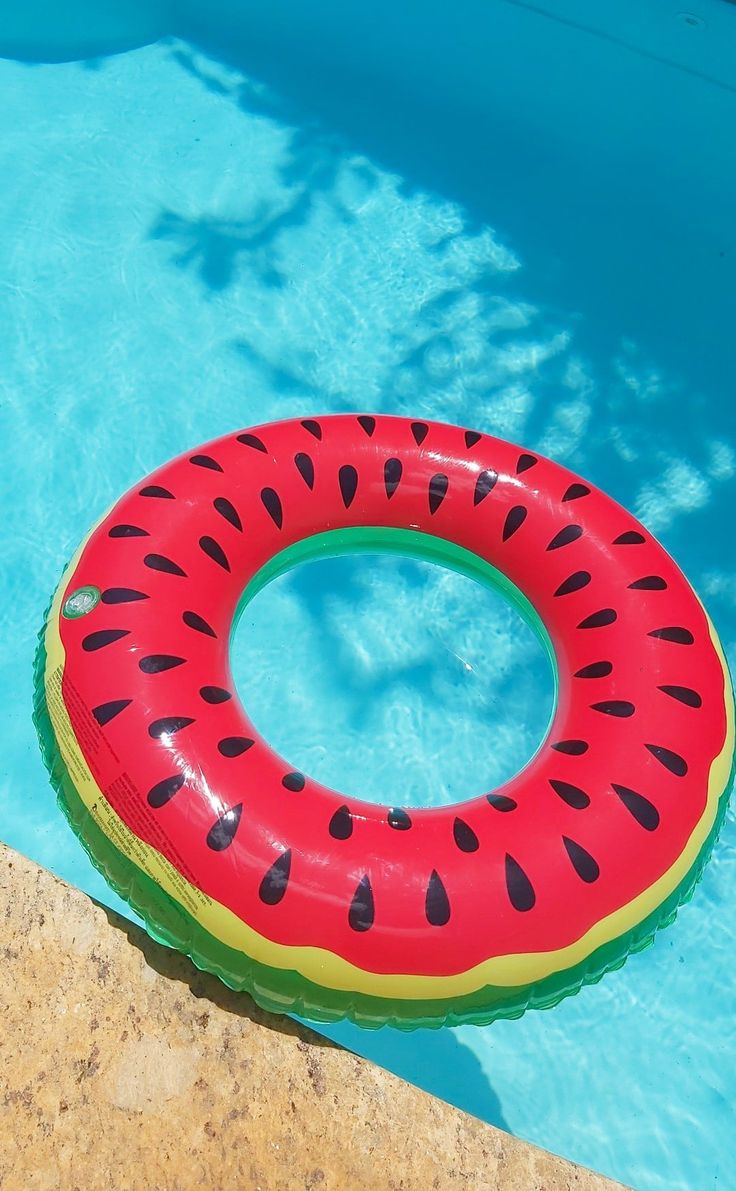 an inflatable watermelon ring sitting on the edge of a swimming pool