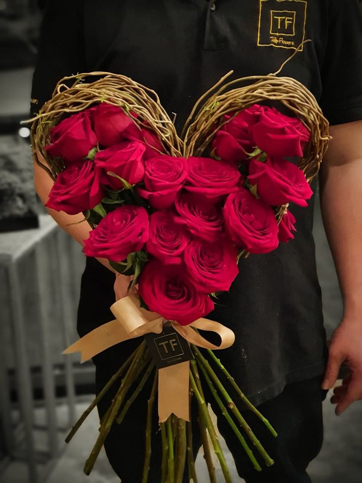 a man holding a heart shaped bouquet of roses