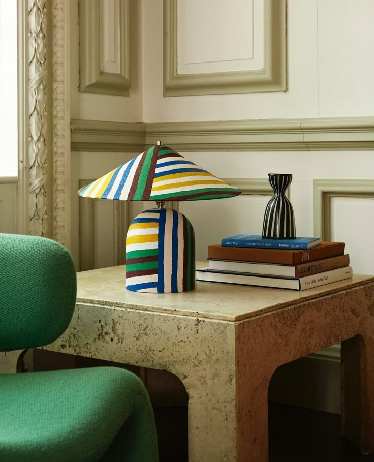 a table topped with books next to a green chair