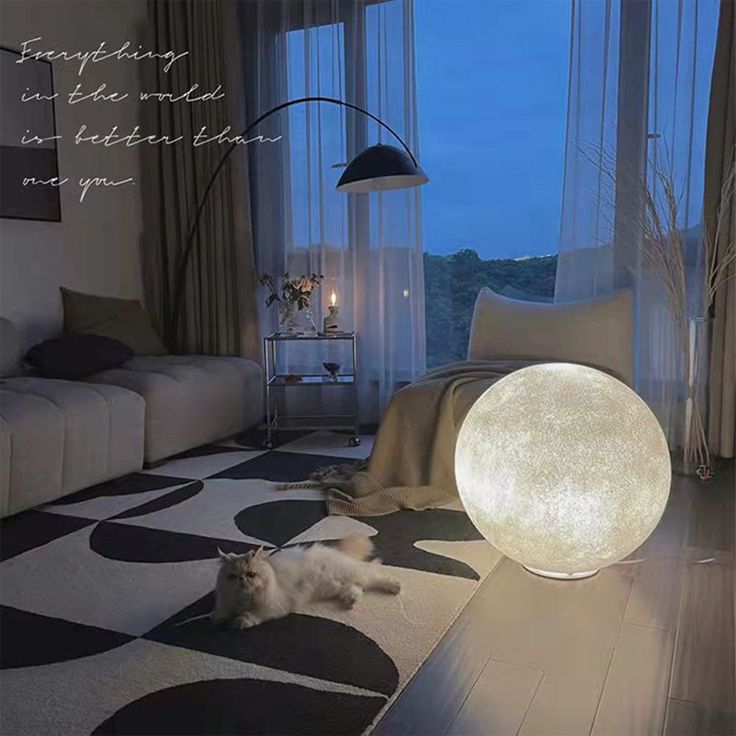 a cat laying on the floor in front of a large moon lamp that is lit up