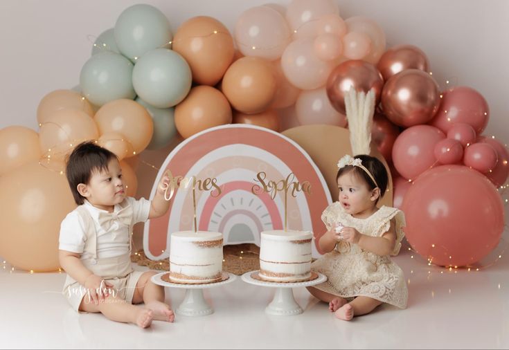 two babies are sitting in front of some cake