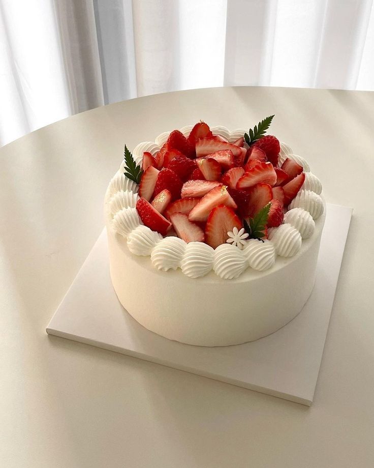 a white cake topped with fresh strawberries on top of a table