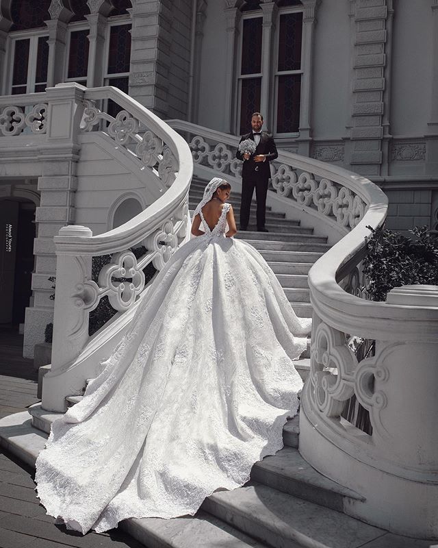 a woman in a wedding dress is standing on the stairs near a man wearing a tuxedo