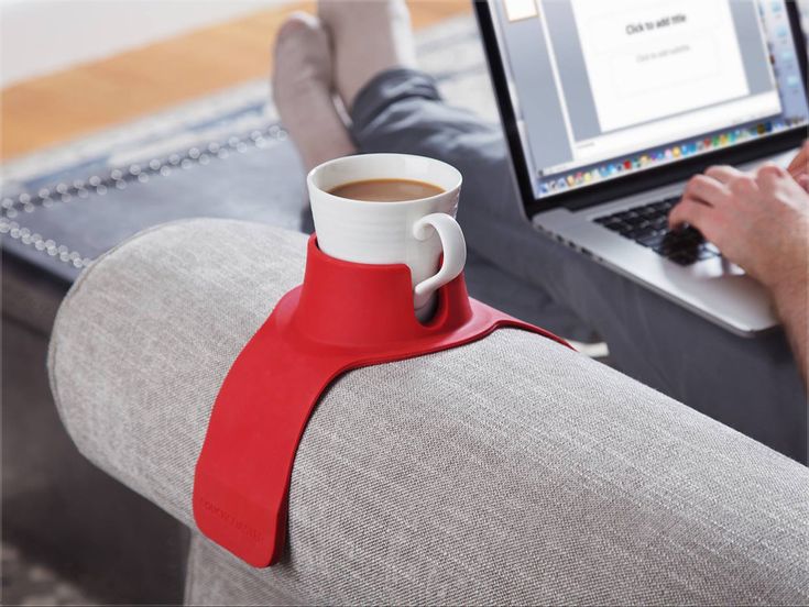 a person sitting on a couch using a laptop with a coffee cup in front of them