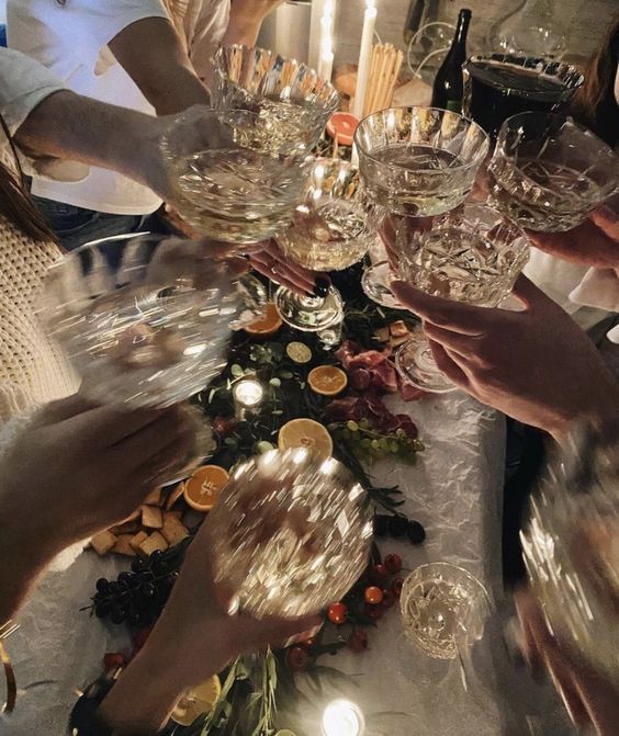 several people are holding wine glasses at a table with food and candles on it for a celebration