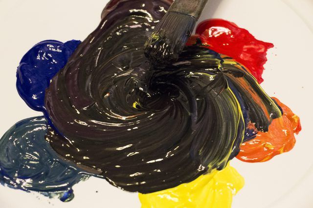 an artist's palette with multiple colors of acrylic paint and a brush