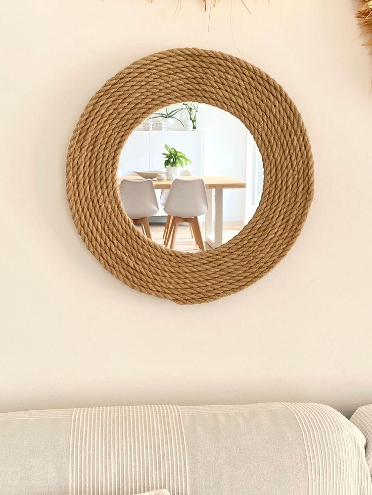 a round mirror hanging on the wall next to a couch and table in a living room