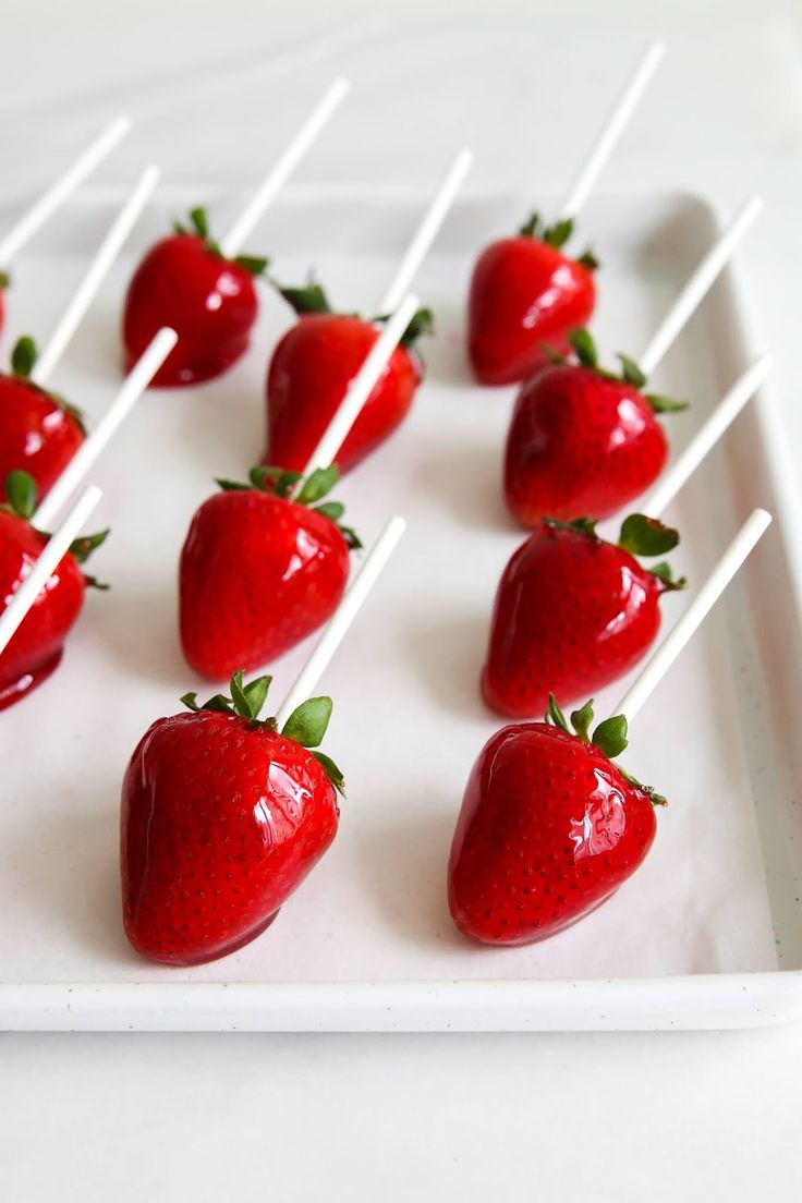 strawberries with toothpicks arranged on a white plate, ready to be eaten