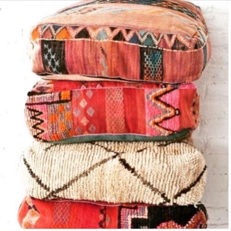 a stack of colorful pillows sitting on top of a white table next to a brick wall