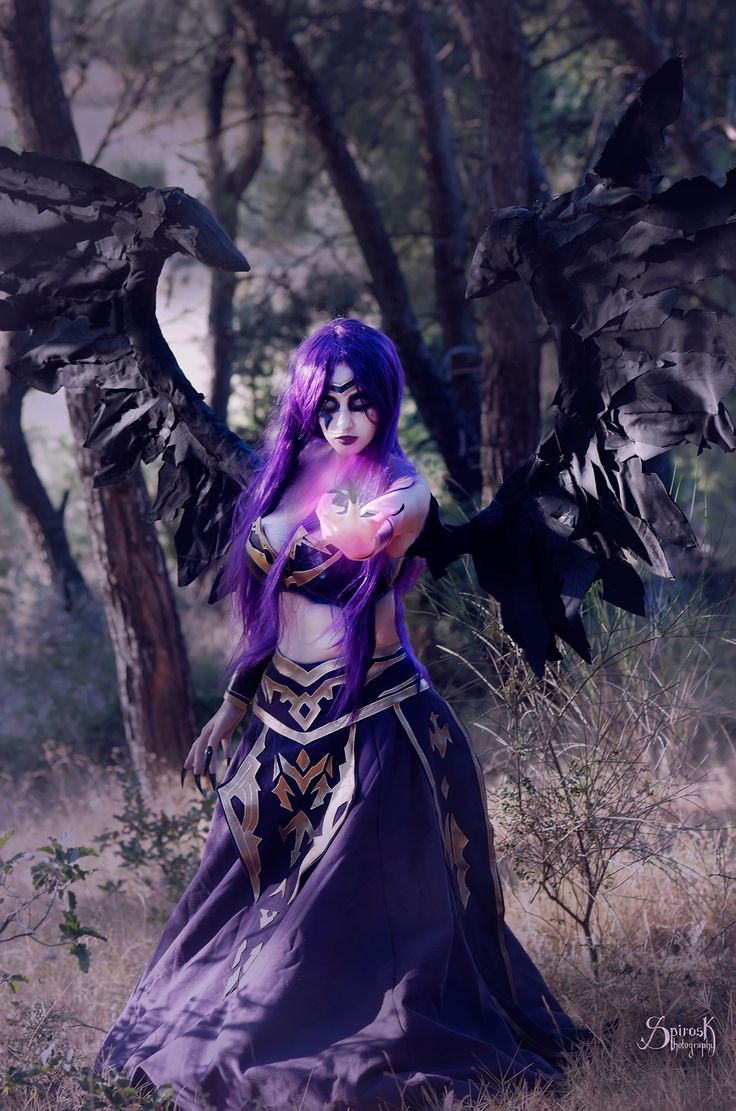 a woman with purple hair and wings standing in the woods, holding a crystal ball