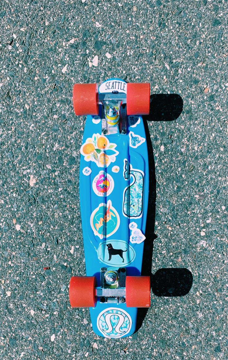 an overhead view of a blue skateboard with stickers on it's wheels