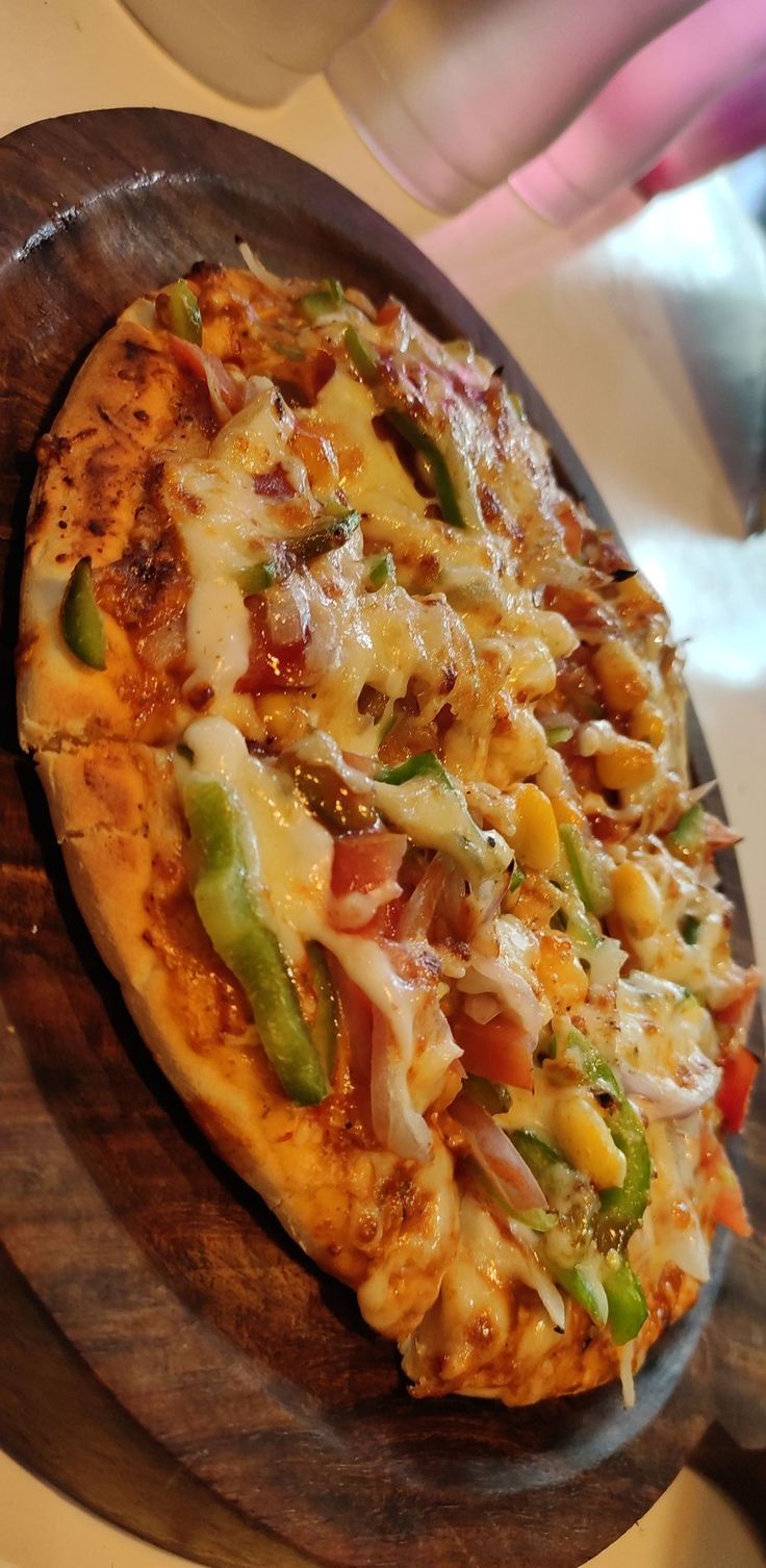 a pizza with many toppings sitting on a wooden platter