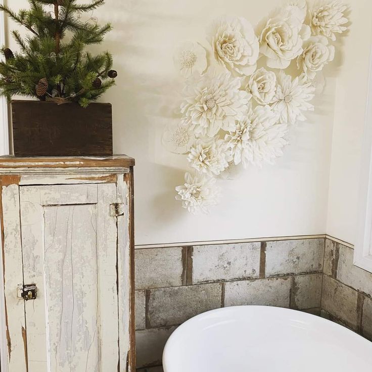 a white bath tub sitting in a bathroom next to a wooden cabinet with flowers on it