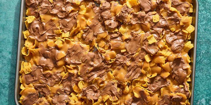 a casserole dish with chocolate and tortilla chips in it on a blue surface