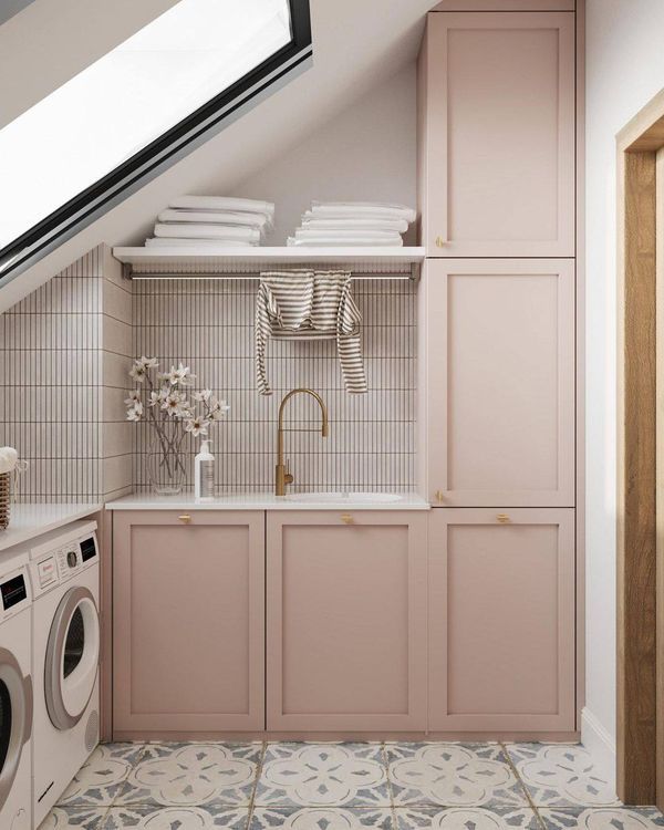 a washer and dryer are in the corner of this laundry room with pink cabinets