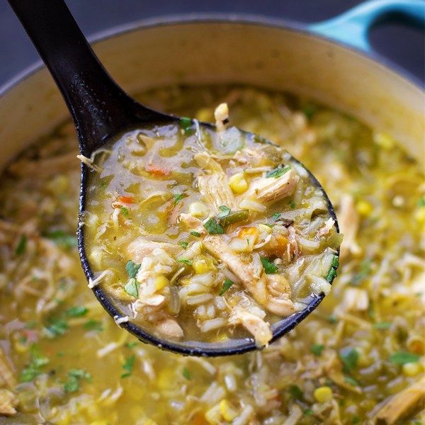 a ladle full of chicken noodle soup is being held by a wooden spoon