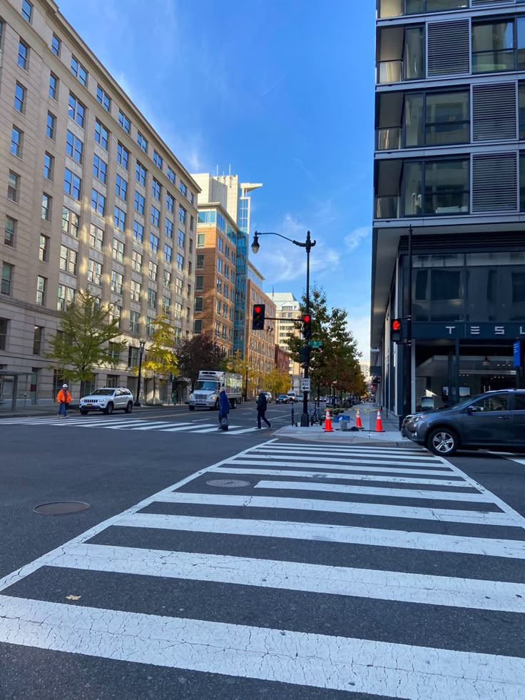 a crosswalk in the middle of a city street with cars parked on both sides