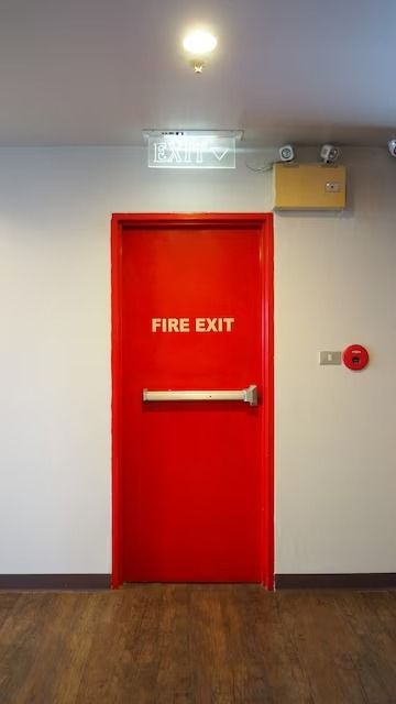 a red fire exit door in an empty room