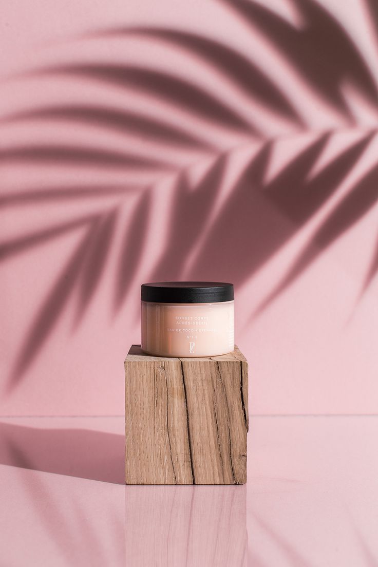 a wooden block with a black lid on it sitting in front of a pink wall