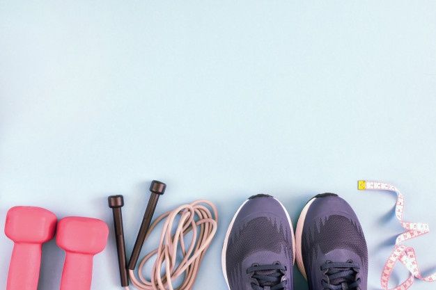 various sports equipment laid out on a light blue background, including shoes, skipping rope and dumbbells