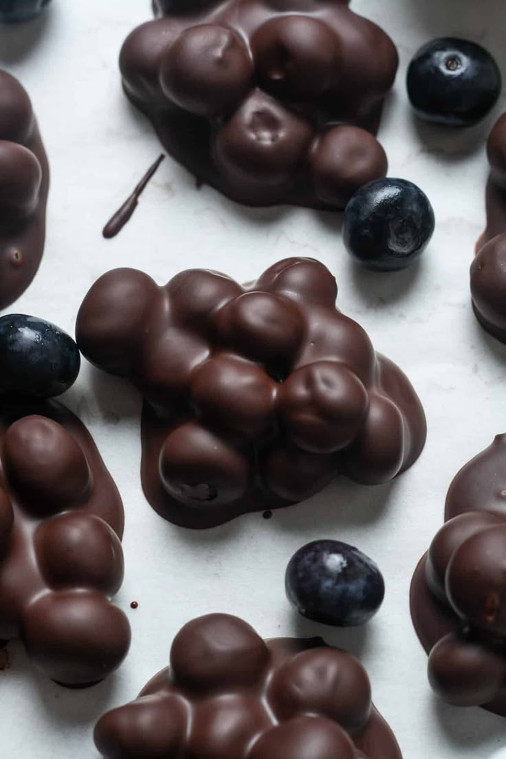 chocolate candies and blueberries are arranged on a white counter top, ready to be eaten