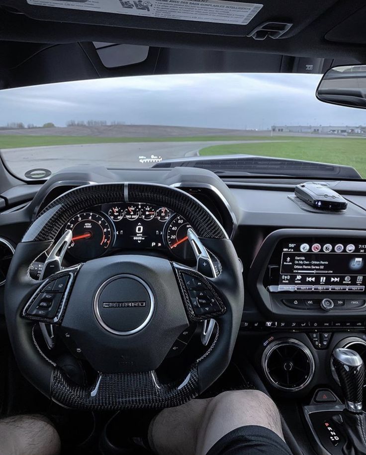 the driver's cockpit of a sports car on a track with grass in the background