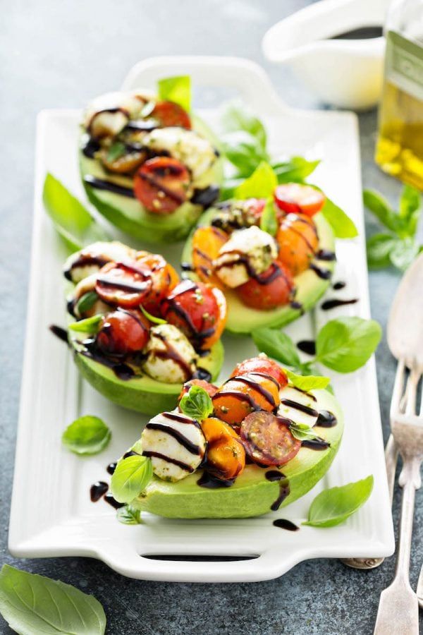 small stuffed avocados with grilled vegetables on them and dressing drizzled over them