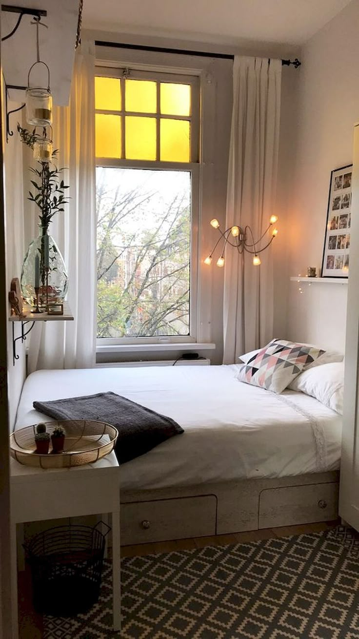 a bedroom with a bed, window and rug on the floor in front of it