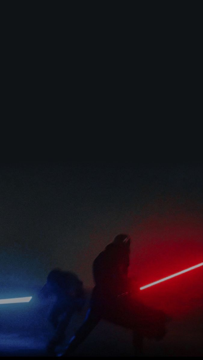 two people in the dark with lightsabed on their backs, one person holding a light saber