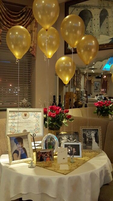 balloons are hanging from the ceiling above a table with pictures and flowers on it in front of a mirror