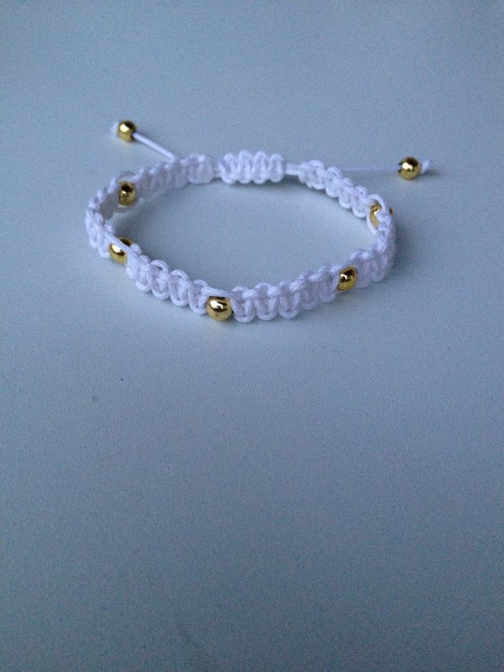 a white beaded bracelet with gold beads on a blue background, close - up