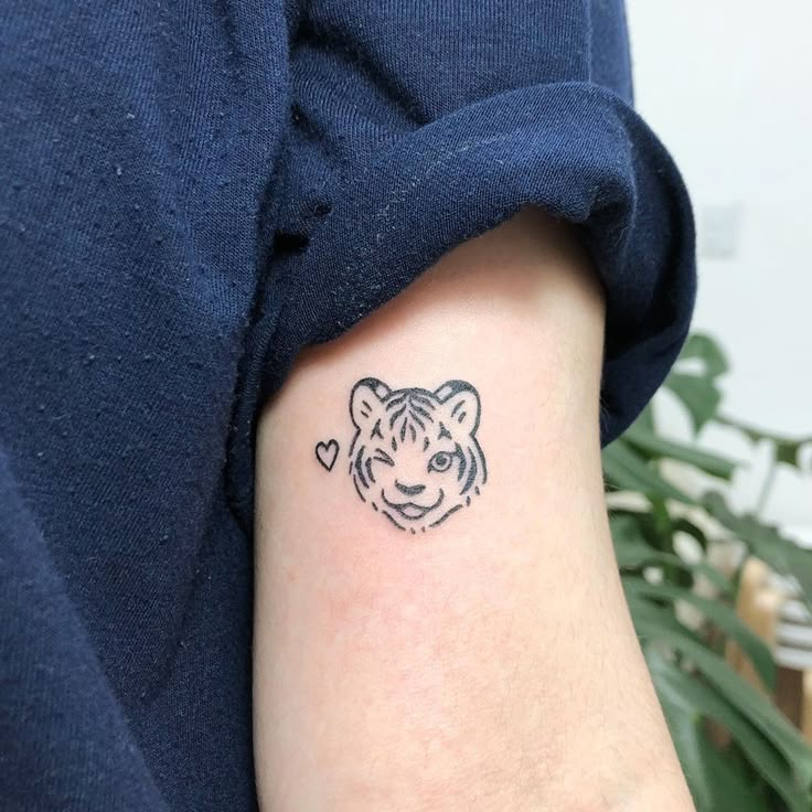 a small tiger head tattoo on the arm