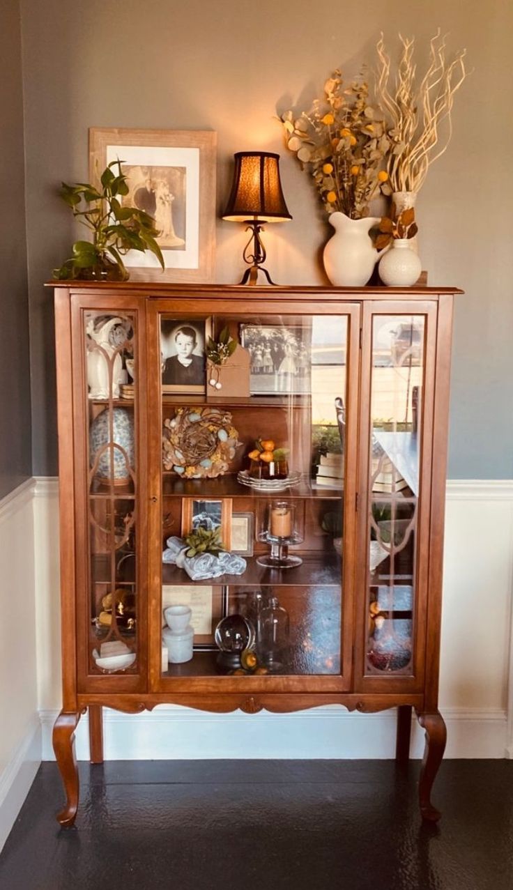 a wooden cabinet with glass doors and flowers on top