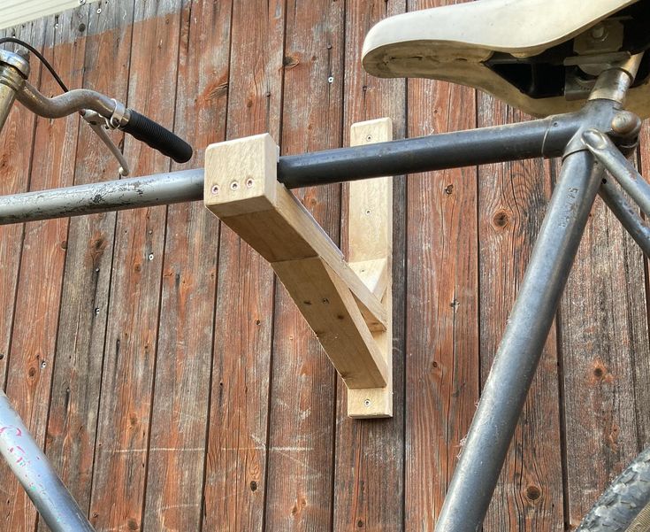 an old bicycle is leaning against a wooden wall and has metal bars attached to it