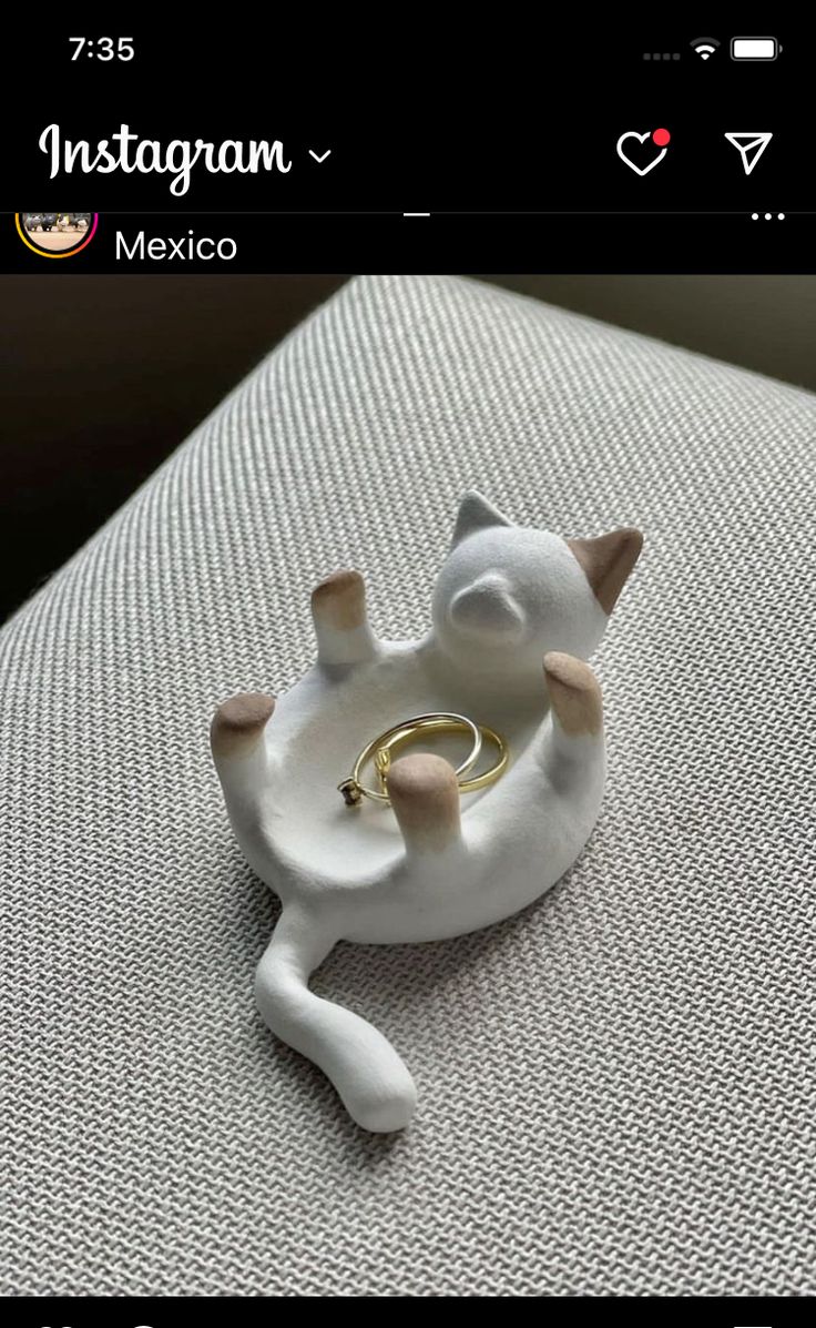 a white cat ring holder sitting on top of a couch