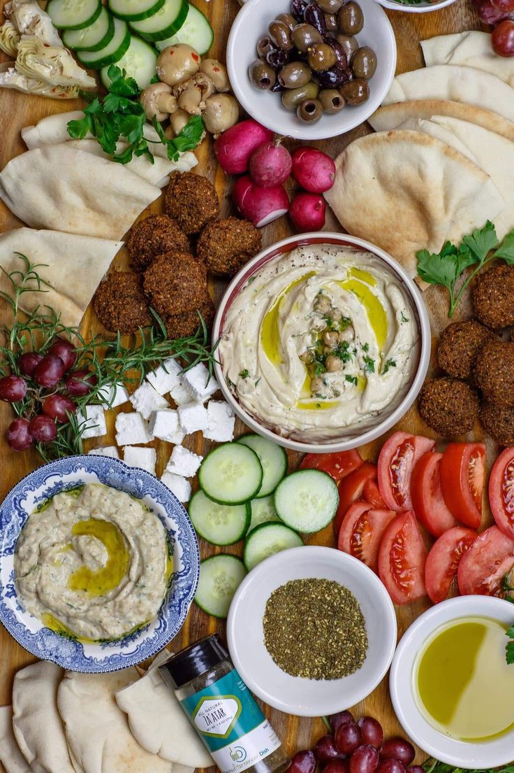 an assortment of food including pita bread, olives, cucumbers and tomatoes