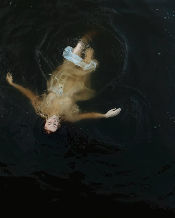 a woman floating in the water with her arms outstretched