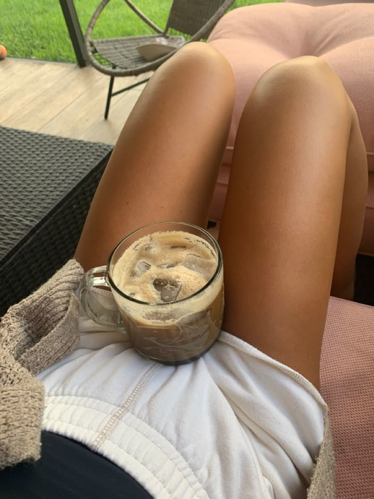 a woman laying on her back with a cup of coffee